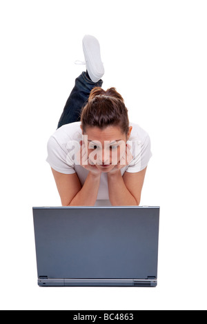 Giovane donna in abbigliamento casual giacente sul suo fronte guardando lo schermo di un computer portatile isolato su sfondo bianco Foto Stock