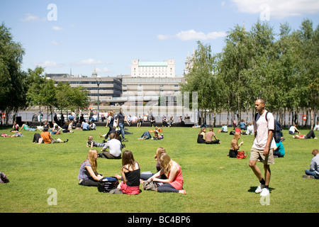 Le persone a rilassarsi in un parco al di fuori della Tate Modern di Londra. Foto Stock