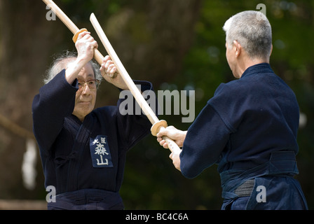 Due uomini sparring con dei bastoni di legno in una formazione swordsmanship esercizio chiamato kenjutsu durante un arti marziali dimostrazione Foto Stock