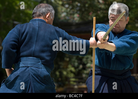 Due uomini sparring con dei bastoni di legno in una formazione swordsmanship esercizio chiamato kenjutsu durante un arti marziali dimostrazione Foto Stock