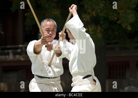 Due uomini sparring con dei bastoni di legno in una formazione swordsmanship esercizio chiamato kenjutsu durante un arti marziali dimostrazione Foto Stock