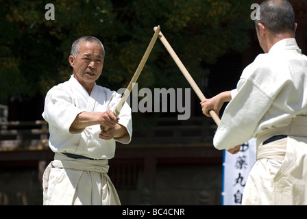 Due uomini sparring con dei bastoni di legno in una formazione swordsmanship esercizio chiamato kenjutsu durante un arti marziali dimostrazione Foto Stock