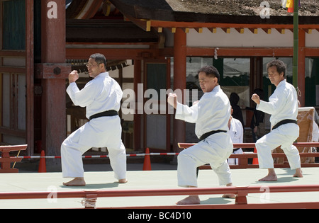 Tre uomini che indossano dogi e cinture nere colpire un pugno di karate posa di punzonatura durante un arti marziali dimostrazione in Kyoto Foto Stock