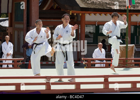 Tre uomini che indossano dogi e cinture nere a colpire il karate kicking pongono durante un arti marziali dimostrazione a Kyoto in Giappone Foto Stock