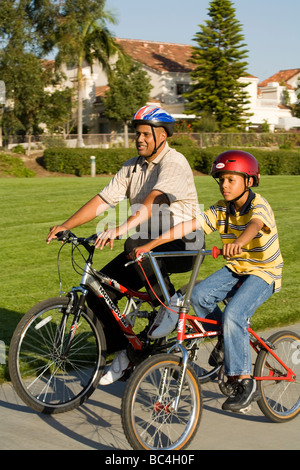 Padre papà bambino equitazione biciclette insieme correre in bici Bicicletta 8-9 anno anni appartenenti a una minoranza etnica California afro-americano di padre negli Stati Uniti Foto Stock