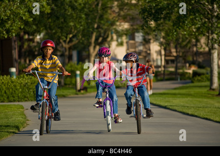 Bambini equitazione biciclette Noleggio biciclette bike insieme outsideU nited membri diversi gruppi etnici due ragazzi una ragazza caucasica California Myrleen Pearson Foto Stock