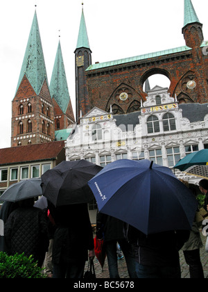 I turisti con ombrelloni guardando il Municipio di Lubecca e di Santa Maria la Chiesa in Germania Foto Stock