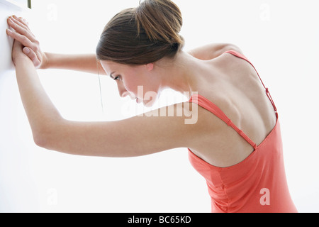 Giovane donna stretching contro la parete Foto Stock