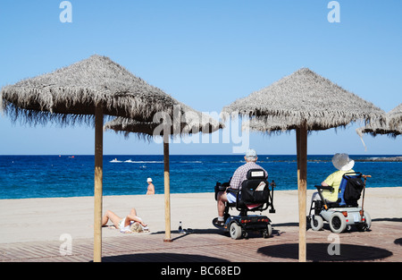 Giovane sulla mobilità scooter guardando il mare dalla spiaggia di Los Cristianos a Tenerife nelle Isole Canarie Foto Stock