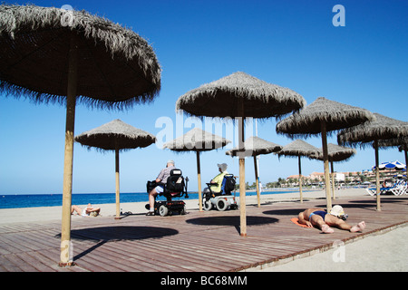 Giovane sulla mobilità scooter guardando il mare dalla spiaggia di Los Cristianos a Tenerife nelle Isole Canarie Foto Stock