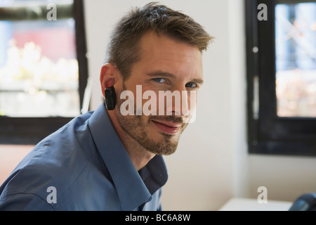 Business man in office che indossa la cuffia, ritratto Foto Stock