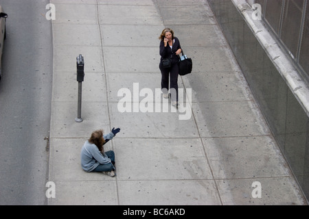 Ricchi poveri dividono la disuguaglianza, Vancouver Canada senzatetto mendicante gastown implacabile di denaro da parte dei turisti, con signora che passa sul telefono cellulare Foto Stock