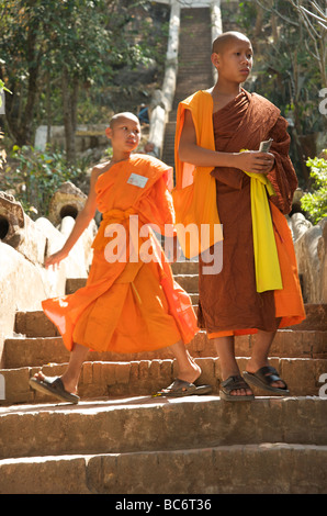 Due novizi monaci buddisti sui gradini di pietra di un tempio a Luang Prabang, Laos Foto Stock