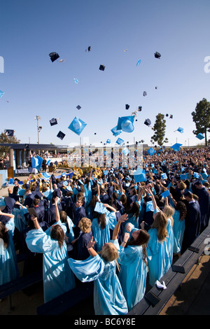 Laurea high school seniors Buttare i tappi tradizionali in aria per festeggiare la fine dell'outdoor inizio esercizi Foto Stock