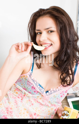 Giovane donna di mangiare patatine Foto Stock