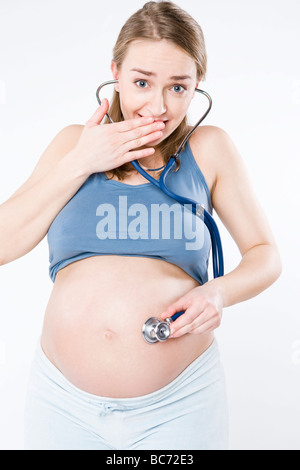 Donna incinta tenendo lo stetoscopio sulla pancia Foto Stock