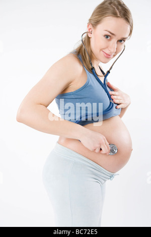 Donna incinta tenendo lo stetoscopio sulla pancia Foto Stock