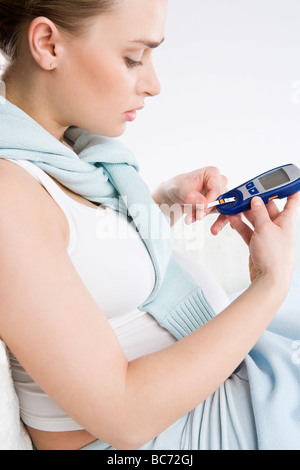 Donna incinta rendendo i livelli di zucchero nel sangue il test Foto Stock