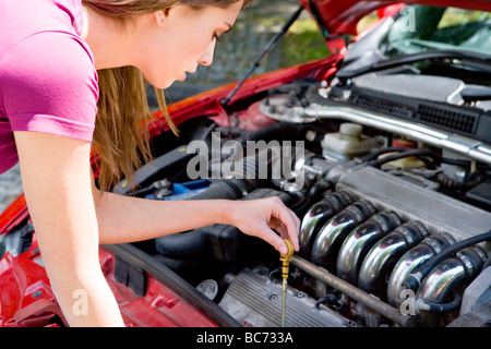 Donna controllo livello olio in auto Foto Stock