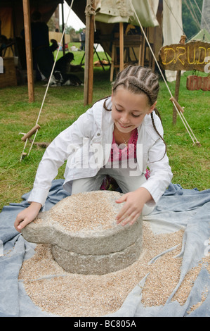 Ragazza giovane macina il grano in farina utilizzando una mola medievale Foto Stock