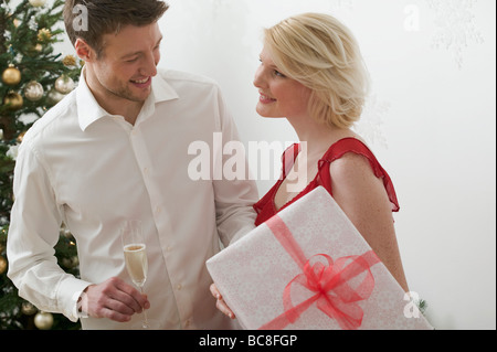 Donna che mantiene grandi pacchi di Natale, uomo con bicchiere di vino - Foto Stock