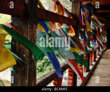 Colorati bandiere di preghiera falp nel vento hangin da un ponte in Bhutan Foto Stock