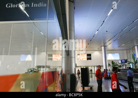I passeggeri del trasporto aereo attendere per i loro bagagli nella sala arrivi dell'aeroporto internazionale Rajiv Gandhi a Hyderabad in India Foto Stock