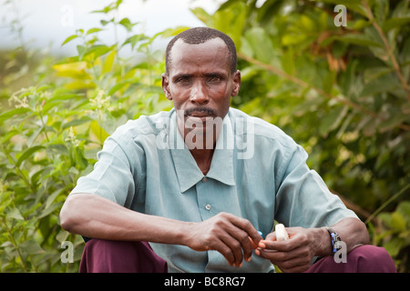 Ritratto di un uomo seduto all'aperto nella vegetazione, villaggio di Kikweni, distretto di Arumeru, regione di Arusha, Tanzania. Foto Stock