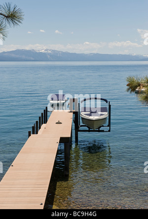 Aprire il pontile in legno sporgente nella tideless acqua dalla costa del lago con una barca alloggiato sulla struttura sollevata in corrispondenza della sua estremità. Foto Stock