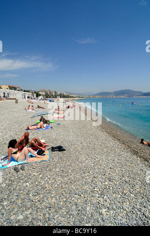 La gente a prendere il sole e godere la famosa spiaggia di ciottoli di Nizza sulla costa Azzurra, Francia meridionale. Foto Stock