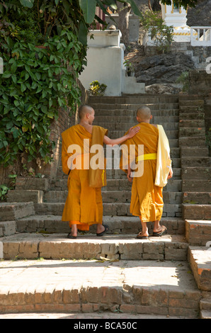 Due monaci novizi salgono i gradini di pietra di un tempio a Luang Prabang Laos Foto Stock