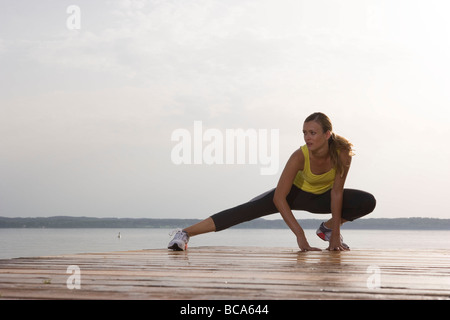 Giovane donna stretching su Jetty prima di jogging Foto Stock