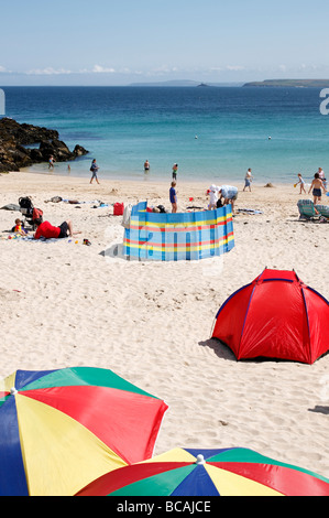 Spiaggia di Porthgwidden in St Ives, Cornwall Inghilterra England Regno Unito. Brollies colorati, frangivento e una spiaggia tenda. Foto Stock