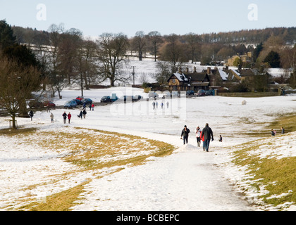 La gente camminare attraverso la neve invernale sul Chatsworth Estate in Derbyshire, England Regno Unito Foto Stock