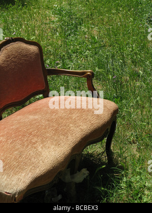 Un vecchio divano danneggiati oggetto di pratiche di dumping nel campo in campagna Foto Stock