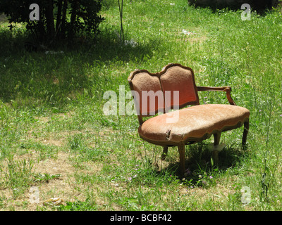 Un vecchio divano danneggiati oggetto di pratiche di dumping nel campo in campagna Foto Stock