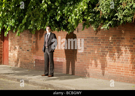 Un adatto giovani professionisti l uomo sta in attesa su una strada urbana nell'ombra, Marylebone, London, England. Foto Stock