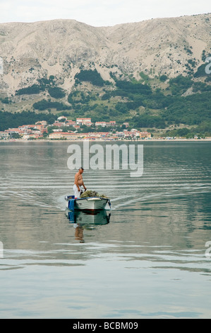 Un pescatore andando indietro nel porto Foto Stock