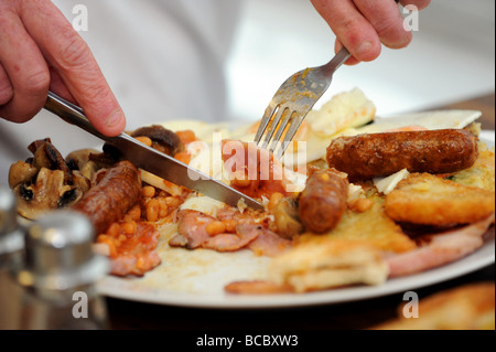 Un uomo di mangiare un gigante la completa prima colazione inglese Foto Stock