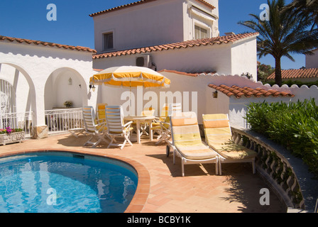 Blu pallido Acqua di piscina area patio e vuoto in giallo e bianco mobili da giardino in una Villa in Empuriabrava Spagna Foto Stock