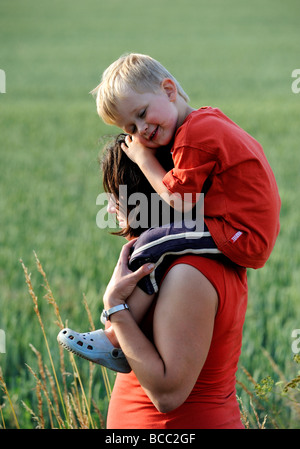 Madre dando figlio Piggyback Ride su prato Foto Stock