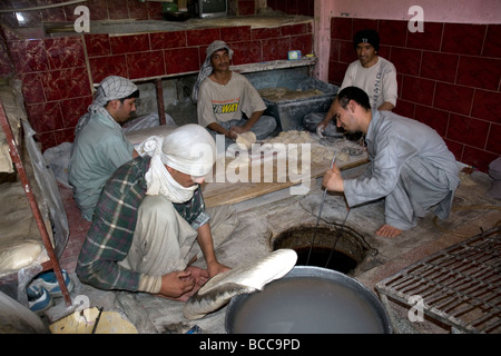 In una panetteria in Chicken Street, Kabul, seduti uomini fanno il pane nazionale, nan, il forno in un buco nel pavimento Foto Stock