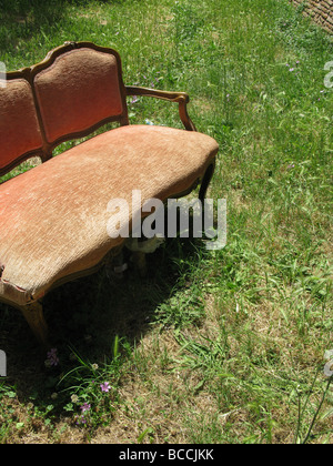 Un vecchio divano danneggiati oggetto di pratiche di dumping nel campo in campagna Foto Stock