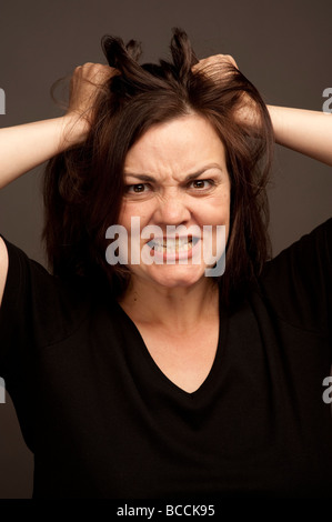 Capelli marrone 30 anno vecchio donna donna la lacerazione al suo marrone capelli in rabbia e frustrazione Foto Stock