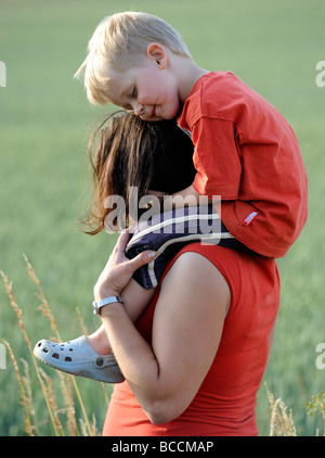 Madre dando figlio Piggyback Ride su prato Foto Stock