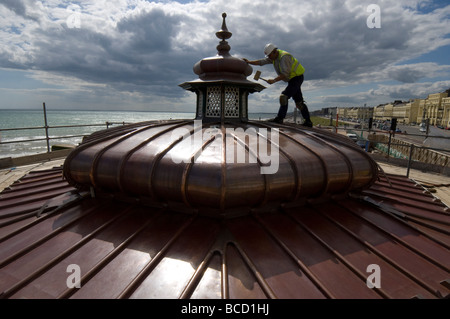 Un operaio martellare un nuovo tetto di rame su di un palco per spettacoli in stile vittoriano su Brighton e Hove lungomare Foto Stock