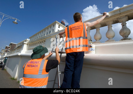 I criminali condannati a fare pittura e decorazione in arancione tabards con comunità payback slogan sul retro Foto Stock