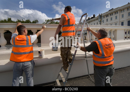 I criminali condannati a fare pittura e decorazione in arancione tabards con comunità payback slogan sul retro Foto Stock