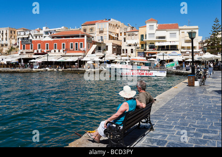 Coppia seduta su una panchina nel vecchio porto veneziano, Chania, North West Coast, Creta, Grecia Foto Stock