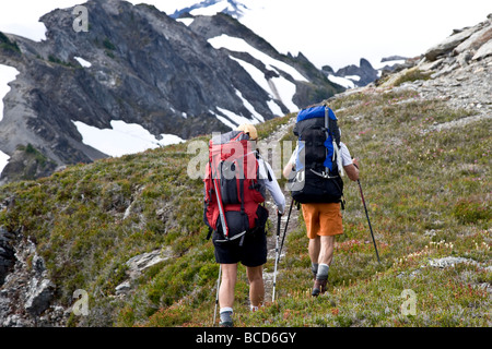 Un uomo e una donna escursione lungo uno stretto sentiero che conduce attraverso la gamma Bailey nel Parco Nazionale di Olympic, nello Stato di Washington. Foto Stock